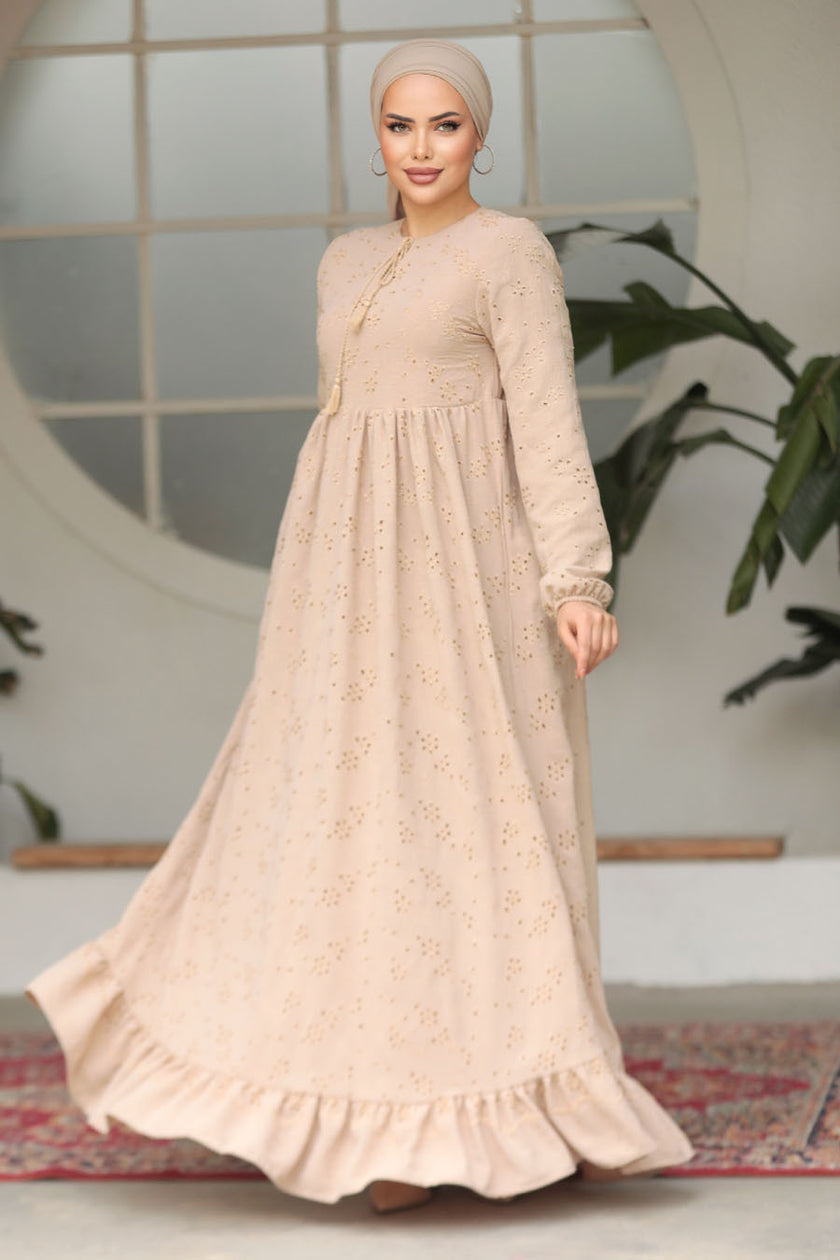Muslim woman wearing a beige embroidered cotton maxi dress with ruffle hem and long sleeves, modest and breathable for casual or formal wear.