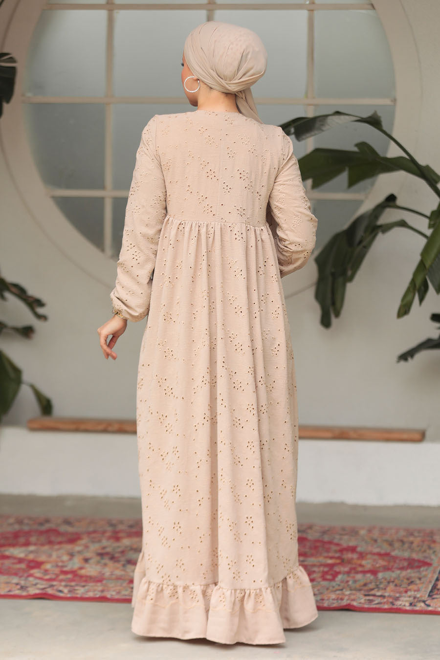 Muslim woman wearing a beige embroidered cotton maxi dress with ruffle hem and long sleeves, modest and breathable for casual or formal wear.