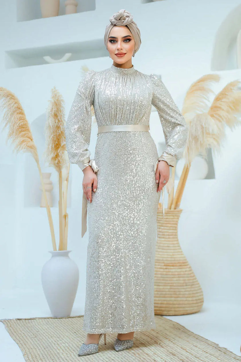 A woman wearing a modest silver sequin maxi gown with a satin waist belt, perfect for formal events and Eid – Zari Hijabeez